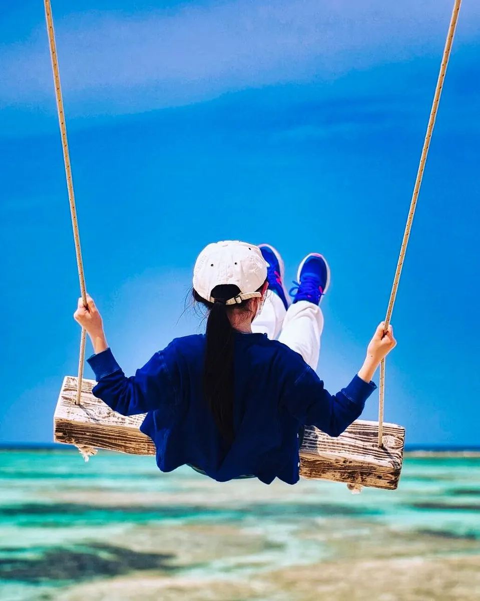 沖縄の碧い海を望むブランコに座る女性・α7S IIIで撮影したシネマティックな風景